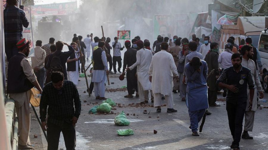 Pendukung mantan Perdana Menteri Pakistan Imran Khan berdiri di tengah asap gas air mata yang ditembakkan oleh polisi selama bentrokan menjelang kemungkinan penangkapan Khan di luar rumahnya, di Lahore, Pakistan 14 Maret 2023. (REUTERS/Mohsin Raza)