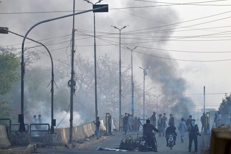 Polisi anti huru hara mencoba memukul mundur pendukung mantan perdana menteri Imran Khan yang berkumpul di luar rumah Khan untuk mencegah petugas menangkapnya, di Lahore, Pakistan pada 14 Maret 2023. Polisi anti huru hara mencoba memukul mundur pendukung mantan perdana menteri Imran Khan yang berkumpul di luar rumah Khan untuk mencegah petugas menangkapnya, di Lahore, Pakistan pada 14 Maret 2023. Para pengunjuk rasa bentrok dengan polisi. Polisi, yang mengenakan pakaian anti huru hara dan memegang perisai, menggunakan meriam air untuk menghalau para aktivis pelempar batu dari partai Pakistan Tehreek-e-Insaf (PTI) Khan, yang telah menguasai pintu masuk utama ke kediaman pemimpin partai mereka. Beberapa pekerja PTI, menurut sumber kepolisian, ditahan. (Rana Irfan Ali/Anadolu Agency via Getty Images)