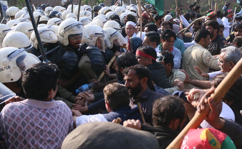 Polisi anti huru hara mencoba memukul mundur pendukung mantan perdana menteri Imran Khan yang berkumpul di luar rumah Khan untuk mencegah petugas menangkapnya, di Lahore, Pakistan pada 14 Maret 2023. Polisi anti huru hara mencoba memukul mundur pendukung mantan perdana menteri Imran Khan yang berkumpul di luar rumah Khan untuk mencegah petugas menangkapnya, di Lahore, Pakistan pada 14 Maret 2023. Para pengunjuk rasa bentrok dengan polisi. Polisi, yang mengenakan pakaian anti huru hara dan memegang perisai, menggunakan meriam air untuk menghalau para aktivis pelempar batu dari partai Pakistan Tehreek-e-Insaf (PTI) Khan, yang telah menguasai pintu masuk utama ke kediaman pemimpin partai mereka. Beberapa pekerja PTI, menurut sumber kepolisian, ditahan. (Rana Irfan Ali/Anadolu Agency via Getty Images)