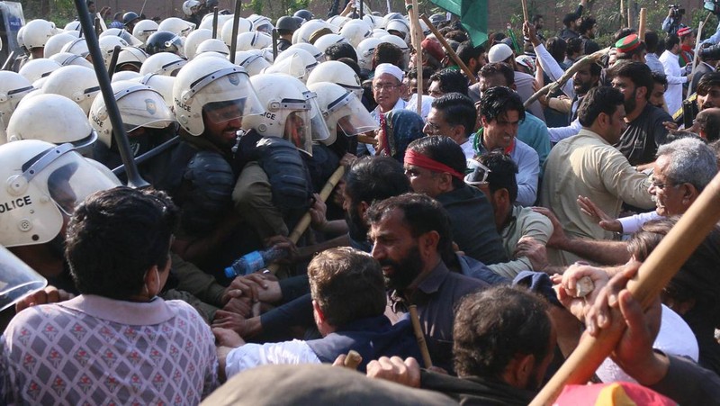 Polisi anti huru hara mencoba memukul mundur pendukung mantan perdana menteri Imran Khan yang berkumpul di luar rumah Khan untuk mencegah petugas menangkapnya, di Lahore, Pakistan pada 14 Maret 2023. Para pengunjuk rasa bentrok dengan polisi. Polisi, yang mengenakan pakaian anti huru hara dan memegang perisai, menggunakan meriam air untuk menghalau para aktivis pelempar batu dari partai Pakistan Tehreek-e-Insaf (PTI) Khan, yang telah menguasai pintu masuk utama ke kediaman pemimpin partai mereka. Beberapa pekerja PTI, menurut sumber kepolisian, ditahan. (Rana Irfan Ali/Anadolu Agency via Getty Images)