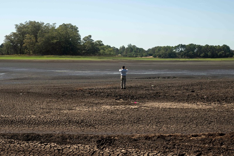 Seorang pria memotret waduk Canelon Grande yang kering di utara Canelones, Uruguay selatan, pada 14 Maret 2023, saat negara itu mengalami kekeringan parah. Seorang pria memotret waduk Canelon Grande yang kering di utara Canelones, Uruguay selatan, pada 14 Maret 2023, saat negara itu mengalami kekeringan parah. - Tujuan utama waduk adalah untuk memasok air minum ke wilayah Metropolitan Montevideo, selain itu juga digunakan dalam sistem irigasi di daerah tersebut. (PABLO PORCIUNCULA/AFP via Getty Images)