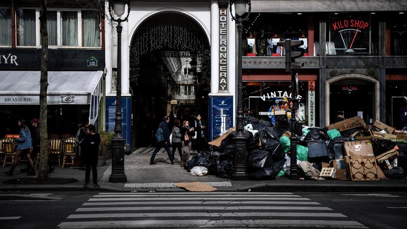 A worker walks past a pile of garbage bags that have been piling up since waste collectors went on strike against the French government's proposed pensions reform, in front of the Eiffel tower in Paris on March 15, 2023. - France faces another day of strikes on march 15, 2023, over highly contested pension reforms which President appears on the verge of pushing through despite months of protests. As the legislation enters the final stretch in parliament, trade unions are set to make another attempt to pressure the government and lawmakers into rejecting the proposed hike in the retirement age to 64. (Photo by Christophe ARCHAMBAULT / AFP) (Photo by CHRISTOPHE ARCHAMBAULT/AFP via Getty Images)
