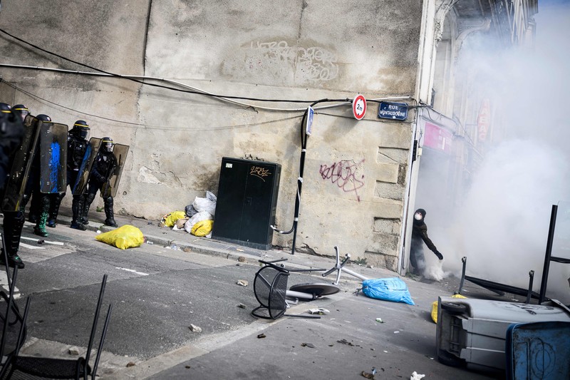 TOPSHOT - A protestor holds an umbrella to protect from teargas during a demonstration on the 8th day of strikes and protests across the country against the government's proposed pensions overhaul, in Nantes, on March 15, 2023. - France faces another day of strikes over highly contested pension reforms which President appears on the verge of pushing through despite months of protests. As the legislation enters the final stretch in parliament, trade unions are set to make another attempt to pressure the government and lawmakers into rejecting the proposed hike in the retirement age to 64. (Photo by LOIC VENANCE / AFP) (Photo by LOIC VENANCE/AFP via Getty Images)