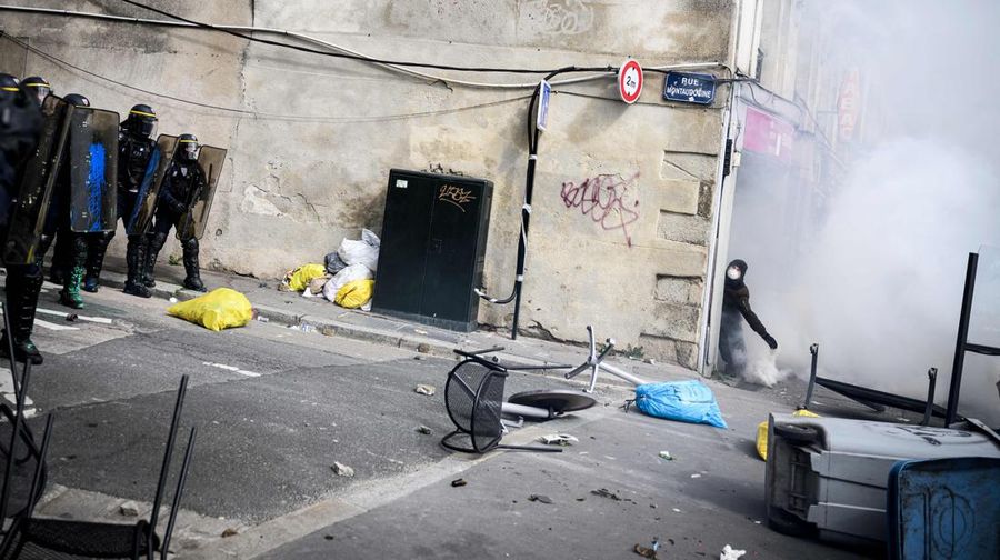 TOPSHOT - A protestor holds an umbrella to protect from teargas during a demonstration on the 8th day of strikes and protests across the country against the government's proposed pensions overhaul, in Nantes, on March 15, 2023. - France faces another day of strikes over highly contested pension reforms which President appears on the verge of pushing through despite months of protests. As the legislation enters the final stretch in parliament, trade unions are set to make another attempt to pressure the government and lawmakers into rejecting the proposed hike in the retirement age to 64. (Photo by LOIC VENANCE / AFP) (Photo by LOIC VENANCE/AFP via Getty Images)