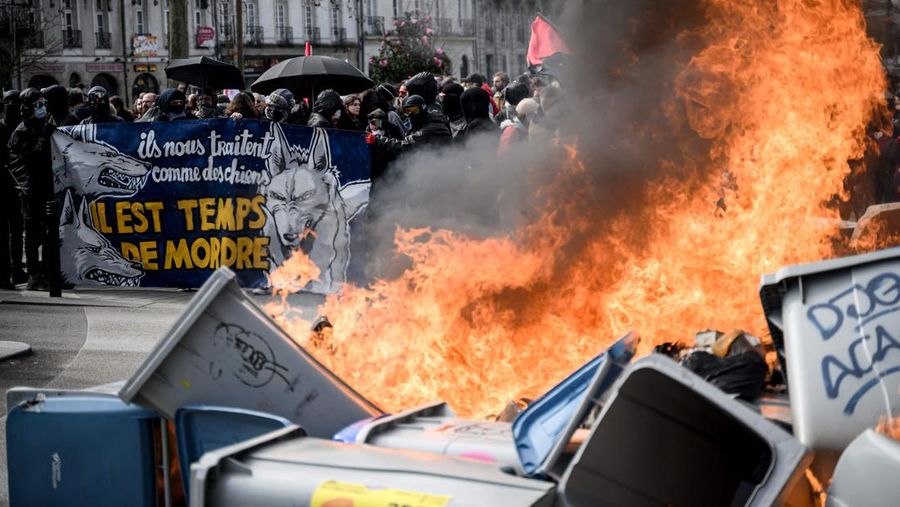 TOPSHOT - A protestor holds an umbrella to protect from teargas during a demonstration on the 8th day of strikes and protests across the country against the government's proposed pensions overhaul, in Nantes, on March 15, 2023. - France faces another day of strikes over highly contested pension reforms which President appears on the verge of pushing through despite months of protests. As the legislation enters the final stretch in parliament, trade unions are set to make another attempt to pressure the government and lawmakers into rejecting the proposed hike in the retirement age to 64. (Photo by LOIC VENANCE / AFP) (Photo by LOIC VENANCE/AFP via Getty Images)