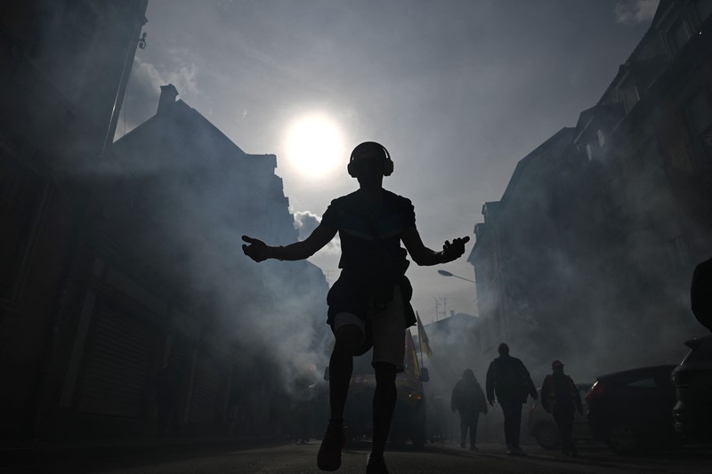 TOPSHOT - A protestor holds an umbrella to protect from teargas during a demonstration on the 8th day of strikes and protests across the country against the government's proposed pensions overhaul, in Nantes, on March 15, 2023. - France faces another day of strikes over highly contested pension reforms which President appears on the verge of pushing through despite months of protests. As the legislation enters the final stretch in parliament, trade unions are set to make another attempt to pressure the government and lawmakers into rejecting the proposed hike in the retirement age to 64. (Photo by LOIC VENANCE / AFP) (Photo by LOIC VENANCE/AFP via Getty Images)