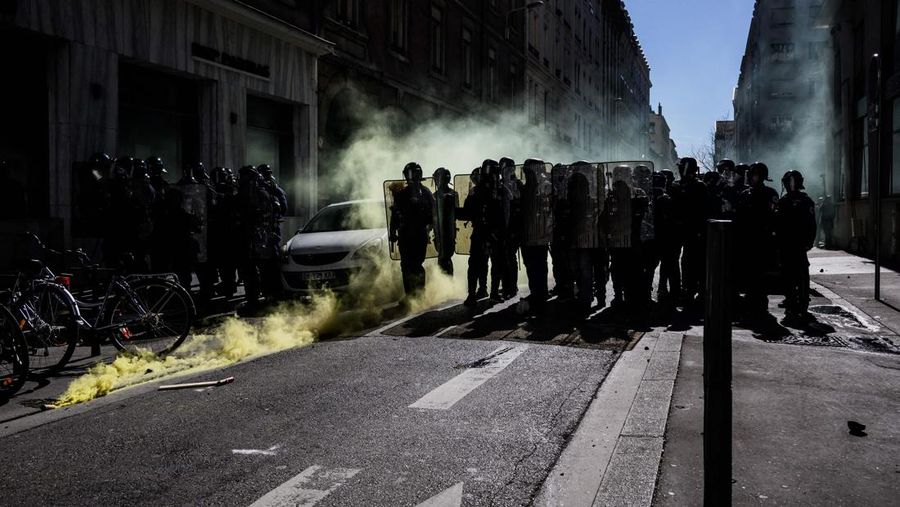 TOPSHOT - A protestor holds an umbrella to protect from teargas during a demonstration on the 8th day of strikes and protests across the country against the government's proposed pensions overhaul, in Nantes, on March 15, 2023. - France faces another day of strikes over highly contested pension reforms which President appears on the verge of pushing through despite months of protests. As the legislation enters the final stretch in parliament, trade unions are set to make another attempt to pressure the government and lawmakers into rejecting the proposed hike in the retirement age to 64. (Photo by LOIC VENANCE / AFP) (Photo by LOIC VENANCE/AFP via Getty Images)
