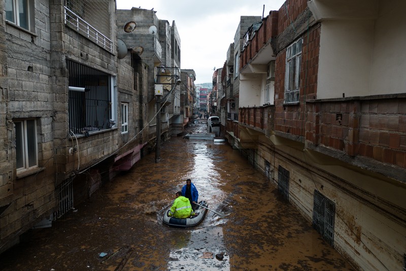 TURKEY-QUAKE-FLOODS People stand at a high pont looking down at the flood waters in Sanliurfa, southeastern Turkey on March 15, 2023. - Flash floods killed at least 10 people living in tents and containers set up across Turkey's quake-hit southeast on March 15, 2023, according to media reports, with at least five people killed and another five missing in Adiyaman and Sanliurfa. (Photo by Demiroren News AAgency / DHA (Demiroren News Agency) / AFP) / - Turkey OUT / RESTRICTED TO EDITORIAL USE - MANDATORY CREDIT