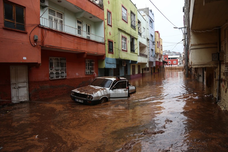People stand at a high pont looking down at the flood waters in Sanliurfa, southeastern Turkey on March 15, 2023. - Flash floods killed at least 10 people living in tents and containers set up across Turkey's quake-hit southeast on March 15, 2023, according to media reports, with at least five people killed and another five missing in Adiyaman and Sanliurfa. (Photo by Demiroren News AAgency / DHA (Demiroren News Agency) / AFP) / - Turkey OUT / RESTRICTED TO EDITORIAL USE - MANDATORY CREDIT 