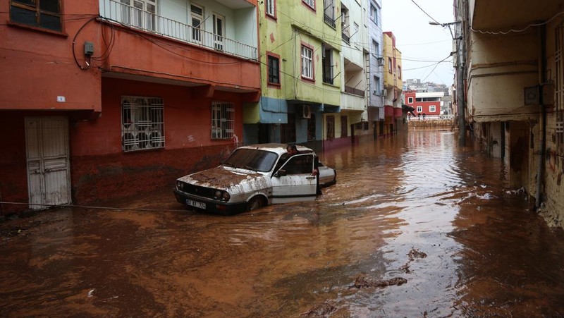 People stand at a high pont looking down at the flood waters in Sanliurfa, southeastern Turkey on March 15, 2023. - Flash floods killed at least 10 people living in tents and containers set up across Turkey's quake-hit southeast on March 15, 2023, according to media reports, with at least five people killed and another five missing in Adiyaman and Sanliurfa. (Photo by Demiroren News AAgency / DHA (Demiroren News Agency) / AFP) / - Turkey OUT / RESTRICTED TO EDITORIAL USE - MANDATORY CREDIT 
