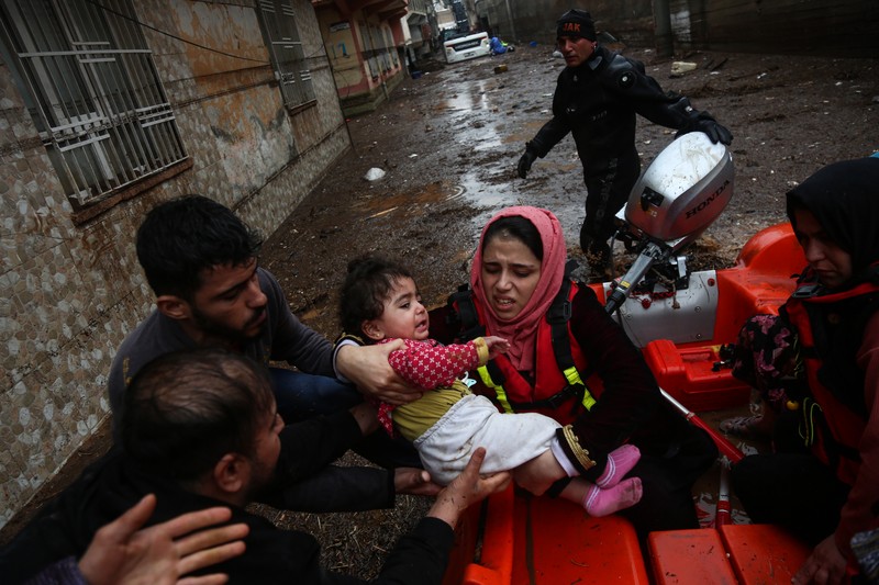 TURKEY-QUAKE-FLOODS People stand at a high pont looking down at the flood waters in Sanliurfa, southeastern Turkey on March 15, 2023. - Flash floods killed at least 10 people living in tents and containers set up across Turkey's quake-hit southeast on March 15, 2023, according to media reports, with at least five people killed and another five missing in Adiyaman and Sanliurfa. (Photo by Demiroren News AAgency / DHA (Demiroren News Agency) / AFP) / - Turkey OUT / RESTRICTED TO EDITORIAL USE - MANDATORY CREDIT