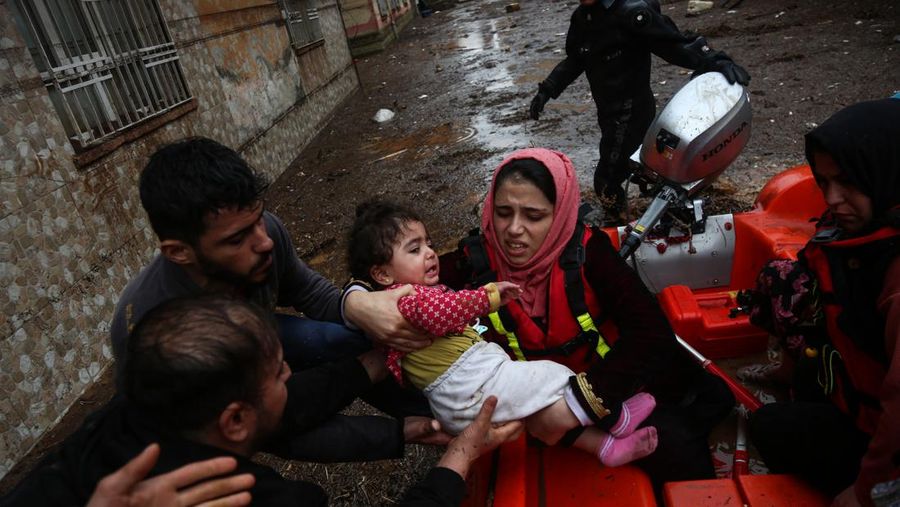 People stand at a high pont looking down at the flood waters in Sanliurfa, southeastern Turkey on March 15, 2023. - Flash floods killed at least 10 people living in tents and containers set up across Turkey's quake-hit southeast on March 15, 2023, according to media reports, with at least five people killed and another five missing in Adiyaman and Sanliurfa. (Photo by Demiroren News AAgency / DHA (Demiroren News Agency) / AFP) / - Turkey OUT / RESTRICTED TO EDITORIAL USE - MANDATORY CREDIT 