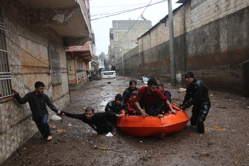 People stand at a high pont looking down at the flood waters in Sanliurfa, southeastern Turkey on March 15, 2023. - Flash floods killed at least 10 people living in tents and containers set up across Turkey's quake-hit southeast on March 15, 2023, according to media reports, with at least five people killed and another five missing in Adiyaman and Sanliurfa. (Photo by Demiroren News AAgency / DHA (Demiroren News Agency) / AFP) / - Turkey OUT / RESTRICTED TO EDITORIAL USE - MANDATORY CREDIT 