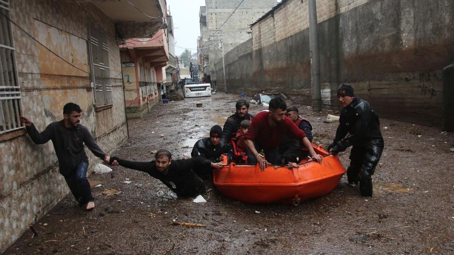 People stand at a high pont looking down at the flood waters in Sanliurfa, southeastern Turkey on March 15, 2023. - Flash floods killed at least 10 people living in tents and containers set up across Turkey's quake-hit southeast on March 15, 2023, according to media reports, with at least five people killed and another five missing in Adiyaman and Sanliurfa. (Photo by Demiroren News AAgency / DHA (Demiroren News Agency) / AFP) / - Turkey OUT / RESTRICTED TO EDITORIAL USE - MANDATORY CREDIT 