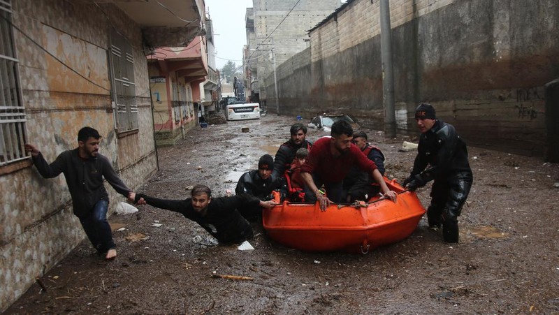 People stand at a high pont looking down at the flood waters in Sanliurfa, southeastern Turkey on March 15, 2023. - Flash floods killed at least 10 people living in tents and containers set up across Turkey's quake-hit southeast on March 15, 2023, according to media reports, with at least five people killed and another five missing in Adiyaman and Sanliurfa. (Photo by Demiroren News AAgency / DHA (Demiroren News Agency) / AFP) / - Turkey OUT / RESTRICTED TO EDITORIAL USE - MANDATORY CREDIT 