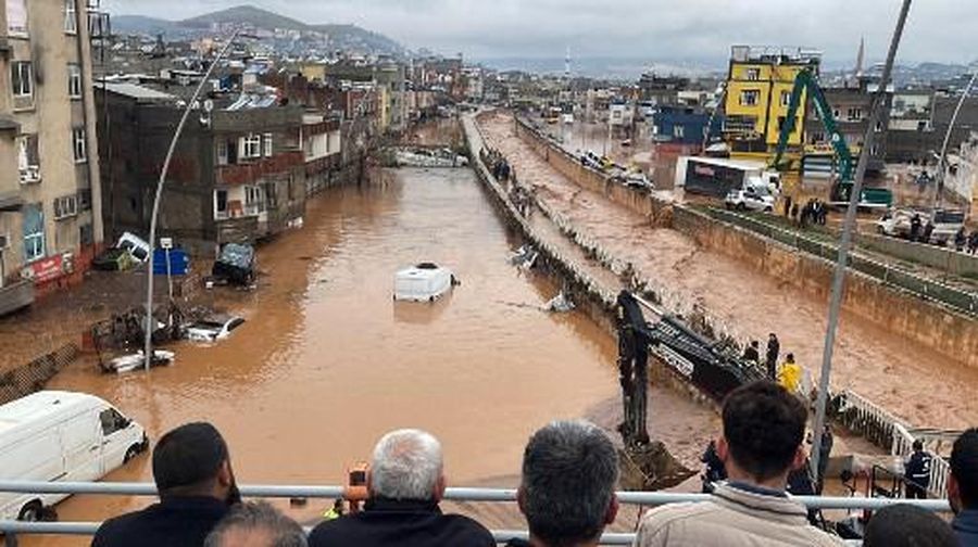 People stand at a high pont looking down at the flood waters in Sanliurfa, southeastern Turkey on March 15, 2023. - Flash floods killed at least 10 people living in tents and containers set up across Turkey's quake-hit southeast on March 15, 2023, according to media reports, with at least five people killed and another five missing in Adiyaman and Sanliurfa. (Photo by Demiroren News AAgency / DHA (Demiroren News Agency) / AFP) / - Turkey OUT / RESTRICTED TO EDITORIAL USE - MANDATORY CREDIT 