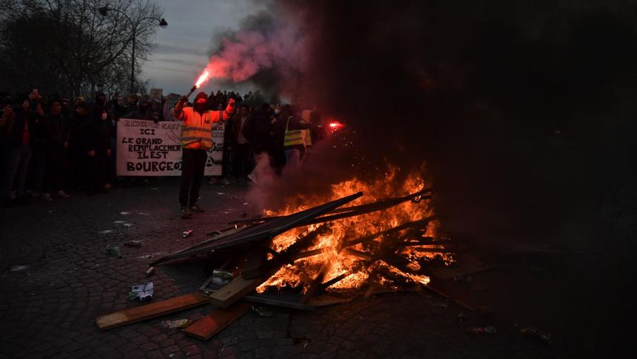 Para pengunjuk rasa membakar saat bentrokan terjadi dengan polisi anti huru hara selama demonstrasi menentang rencana pemerintah Prancis untuk menaikkan usia pensiun resmi di Paris, pada 16 Maret 2023. (Firas Abdullah/Anadolu Agency via Getty Images)
