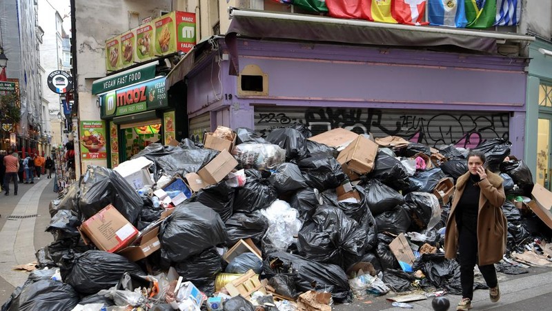Tong sampah penuh dengan sampah di jalanan saat pemungut melanjutkan pemogokan mereka di Paris, Prancis pada 17 Maret 2023. Pemungut sampah telah bergabung dalam pemogokan besar-besaran di seluruh Prancis menentang rencana reformasi pensiun. (Mustafa Yalcin/Anadolu Agency via Getty Images)
