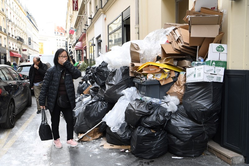 Pejalan kaki menutupi hidung mereka saat mereka berjalan melewati sampah yang berbau busuk di jalan saat para pemulung mogok menentang reformasi pensiun, di distrik 9 Paris pada 17 Maret 2023. Pejalan kaki menutupi hidung mereka saat mereka berjalan melewati sampah yang berbau busuk di jalan saat para pemulung mogok menentang reformasi pensiun, di distrik 9 Paris pada 17 Maret 2023. - Prancis memaksa pemulung sampah Paris untuk kembali bekerja setelah pemogokan selama berhari-hari menentang reformasi pensiun. Pekerja keluar dari pekerjaan sebagai protes terhadap rencana Presiden Emmanuel Macron untuk mereformasi sistem pensiun, dengan langkah-langkah utama menaikkan usia pensiun resmi menjadi 64 tahun dan meningkatkan jumlah tahun yang harus dibayar orang untuk menerima pensiun penuh. (BERTRAND GUAY/AFP via Getty Images)