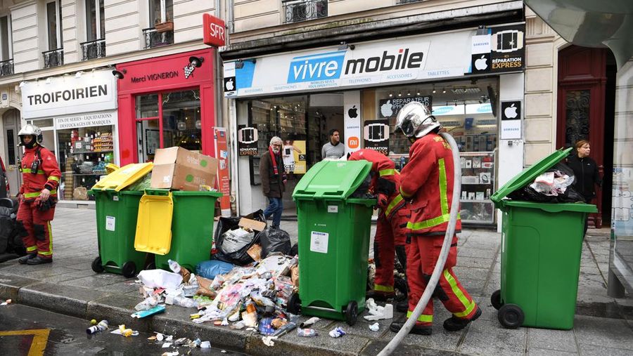 Pejalan kaki menutupi hidung mereka saat mereka berjalan melewati sampah yang berbau busuk di jalan saat para pemulung mogok menentang reformasi pensiun, di distrik 9 Paris pada 17 Maret 2023. - Prancis memaksa pemulung sampah Paris untuk kembali bekerja setelah pemogokan selama berhari-hari menentang reformasi pensiun. Pekerja keluar dari pekerjaan sebagai protes terhadap rencana Presiden Emmanuel Macron untuk mereformasi sistem pensiun, dengan langkah-langkah utama menaikkan usia pensiun resmi menjadi 64 tahun dan meningkatkan jumlah tahun yang harus dibayar orang untuk menerima pensiun penuh. (BERTRAND GUAY/AFP via Getty Images)