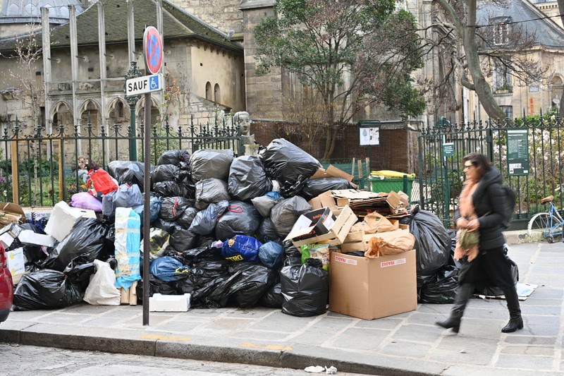 Pejalan kaki menutupi hidung mereka saat mereka berjalan melewati sampah yang berbau busuk di jalan saat para pemulung mogok menentang reformasi pensiun, di distrik 9 Paris pada 17 Maret 2023. Pejalan kaki menutupi hidung mereka saat mereka berjalan melewati sampah yang berbau busuk di jalan saat para pemulung mogok menentang reformasi pensiun, di distrik 9 Paris pada 17 Maret 2023. - Prancis memaksa pemulung sampah Paris untuk kembali bekerja setelah pemogokan selama berhari-hari menentang reformasi pensiun. Pekerja keluar dari pekerjaan sebagai protes terhadap rencana Presiden Emmanuel Macron untuk mereformasi sistem pensiun, dengan langkah-langkah utama menaikkan usia pensiun resmi menjadi 64 tahun dan meningkatkan jumlah tahun yang harus dibayar orang untuk menerima pensiun penuh. (BERTRAND GUAY/AFP via Getty Images)