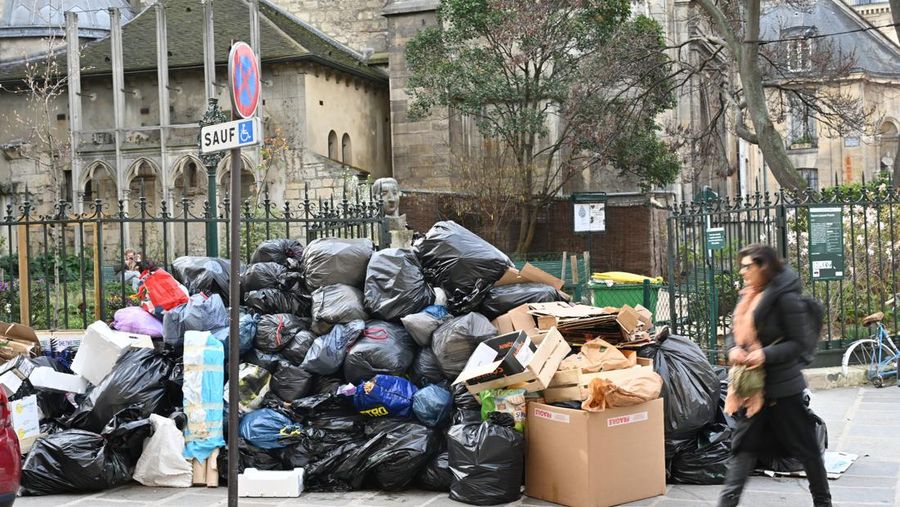 Pejalan kaki menutupi hidung mereka saat mereka berjalan melewati sampah yang berbau busuk di jalan saat para pemulung mogok menentang reformasi pensiun, di distrik 9 Paris pada 17 Maret 2023. - Prancis memaksa pemulung sampah Paris untuk kembali bekerja setelah pemogokan selama berhari-hari menentang reformasi pensiun. Pekerja keluar dari pekerjaan sebagai protes terhadap rencana Presiden Emmanuel Macron untuk mereformasi sistem pensiun, dengan langkah-langkah utama menaikkan usia pensiun resmi menjadi 64 tahun dan meningkatkan jumlah tahun yang harus dibayar orang untuk menerima pensiun penuh. (BERTRAND GUAY/AFP via Getty Images)