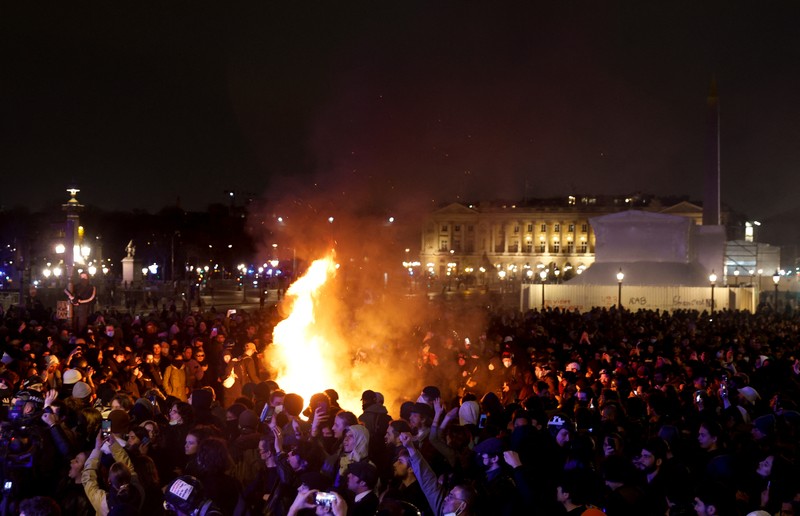 Seorang pengunjuk rasa memegang gambar Presiden Prancis Emmanuel Macron di dekat api selama demonstrasi di Place de la Concorde untuk memprotes penggunaan pasal 49.3 oleh pemerintah Prancis, klausul khusus dalam Konstitusi Prancis, untuk mendorong RUU reformasi pensiun melalui Majelis Nasional tanpa pemungutan suara oleh anggota parlemen, di Paris, Prancis, 17 Maret 2023. Seorang pengunjuk rasa memegang gambar Presiden Prancis Emmanuel Macron di dekat api selama demonstrasi di Place de la Concorde untuk memprotes penggunaan pasal 49.3 oleh pemerintah Prancis, klausul khusus dalam Konstitusi Prancis, untuk mendorong RUU reformasi pensiun melalui Majelis Nasional tanpa pemungutan suara oleh anggota parlemen, di Paris, Prancis, 17 Maret 2023. (REUTERS/Gonzalo Fuentes)