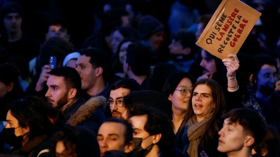 Seorang pengunjuk rasa memegang gambar Presiden Prancis Emmanuel Macron di dekat api selama demonstrasi di Place de la Concorde untuk memprotes penggunaan pasal 49.3 oleh pemerintah Prancis, klausul khusus dalam Konstitusi Prancis, untuk mendorong RUU reformasi pensiun melalui Majelis Nasional tanpa pemungutan suara oleh anggota parlemen, di Paris, Prancis, 17 Maret 2023. (REUTERS/Gonzalo Fuentes)
