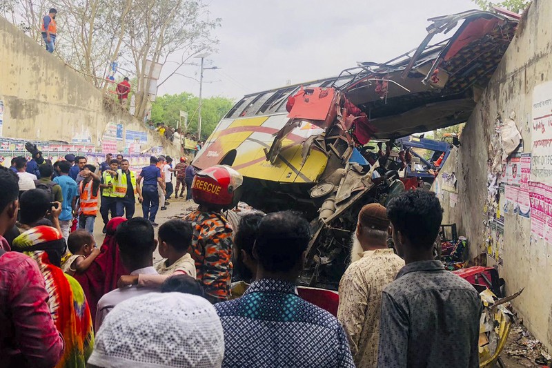 Petugas pemadam kebakaran memadamkan bus yang mengalami kecelakaan di Madaripur pada 19 Maret 2023. - Setidaknya 17 orang tewas dan hingga 25 lainnya luka-luka pada 19 Maret di Bangladesh setelah sebuah bus menabrak pagar jalan raya dan jatuh ke selokan pinggir jalan, menurut polisi. (-/AFP via Getty Images)