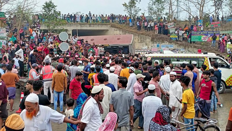 Petugas pemadam kebakaran memadamkan bus yang mengalami kecelakaan di Madaripur pada 19 Maret 2023. - Setidaknya 17 orang tewas dan hingga 25 lainnya luka-luka pada 19 Maret di Bangladesh setelah sebuah bus menabrak pagar jalan raya dan jatuh ke selokan pinggir jalan, menurut polisi. (-/AFP via Getty Images)