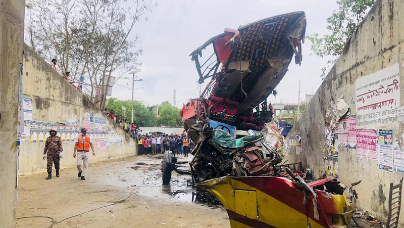 Petugas pemadam kebakaran memadamkan bus yang mengalami kecelakaan di Madaripur pada 19 Maret 2023. - Setidaknya 17 orang tewas dan hingga 25 lainnya luka-luka pada 19 Maret di Bangladesh setelah sebuah bus menabrak pagar jalan raya dan jatuh ke selokan pinggir jalan, menurut polisi. (-/AFP via Getty Images)