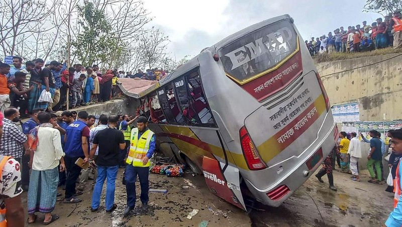 Petugas pemadam kebakaran memadamkan bus yang mengalami kecelakaan di Madaripur pada 19 Maret 2023. - Setidaknya 17 orang tewas dan hingga 25 lainnya luka-luka pada 19 Maret di Bangladesh setelah sebuah bus menabrak pagar jalan raya dan jatuh ke selokan pinggir jalan, menurut polisi. (-/AFP via Getty Images)