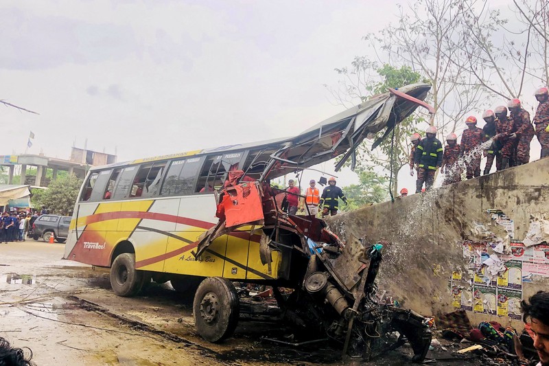 Petugas pemadam kebakaran memadamkan bus yang mengalami kecelakaan di Madaripur pada 19 Maret 2023. - Setidaknya 17 orang tewas dan hingga 25 lainnya luka-luka pada 19 Maret di Bangladesh setelah sebuah bus menabrak pagar jalan raya dan jatuh ke selokan pinggir jalan, menurut polisi. Petugas pemadam kebakaran memadamkan bus yang mengalami kecelakaan di Madaripur pada 19 Maret 2023. - Setidaknya 17 orang tewas dan hingga 25 lainnya luka-luka pada 19 Maret di Bangladesh setelah sebuah bus menabrak pagar jalan raya dan jatuh ke selokan pinggir jalan, menurut polisi. (-/AFP via Getty Images)