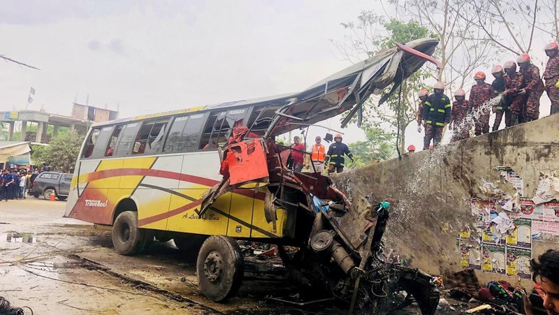 Petugas pemadam kebakaran memadamkan bus yang mengalami kecelakaan di Madaripur pada 19 Maret 2023. - Setidaknya 17 orang tewas dan hingga 25 lainnya luka-luka pada 19 Maret di Bangladesh setelah sebuah bus menabrak pagar jalan raya dan jatuh ke selokan pinggir jalan, menurut polisi. (-/AFP via Getty Images)