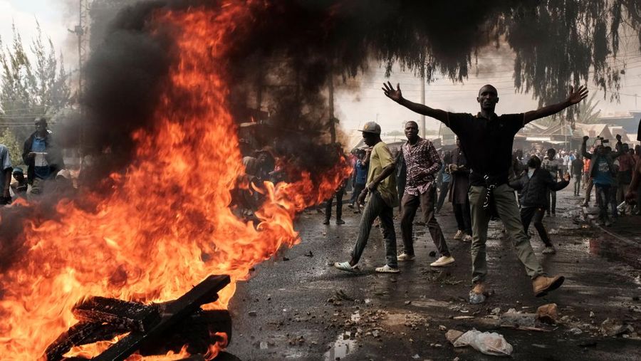 Seorang pengunjuk rasa memberi isyarat di sebelah barikade yang terbakar selama rapat umum massal yang diserukan oleh pemimpin oposisi Raila Odinga yang mengklaim pemilihan presiden Kenya terakhir dicuri darinya dan menyalahkan pemerintah atas kenaikan biaya hidup di Kibera, Nairobi pada 20 Maret 2023. (YASUYOSHI CHIBA/AFP via Getty Images)