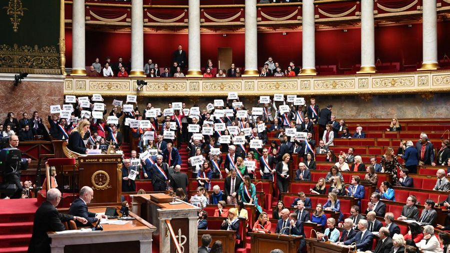 Anggota kelompok parlemen Majelis Nasional La France Insoumise (LFI) dan koalisi sayap kiri NUPES (Persatuan Ekologi dan Sosial Rakyat Baru) memegang tanda bertuliskan 