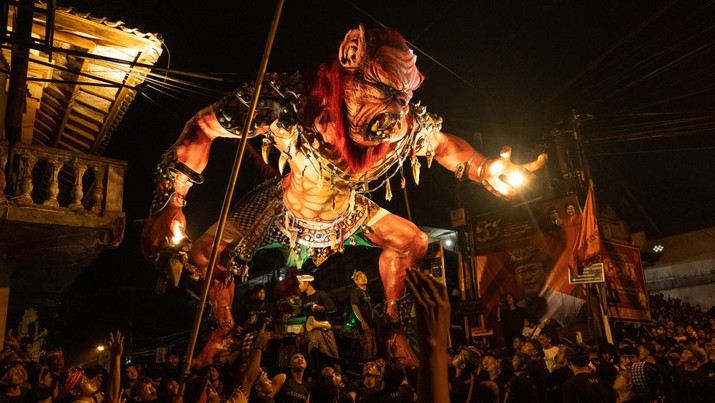 Pemuda Bali membawa ogoh-ogoh, boneka raksasa yang tampak mengancam saat pawai ogoh-ogoh pada malam Nyepi, Hari Raya Nyepi umat Hindu Bali yang menandai datangnya tahun baru Saka bulan pada 20 Maret 2023 di Tegalalang Desa, Gianyar, Bali, Indonesia. Umat Hindu di Bali melakukan serangkaian ritual pada awal Maret untuk merayakan tahun baru Imlek yang berpuncak pada perayaan Nyepi. Ogoh-ogoh menjadi salah satu pawai di awal tahun 1980-an. Sebelumnya, para peserta berkeliaran di jalan-jalan membawa obor bambu dan membuat suara keras dengan instrumen perkusi untuk menakut-nakuti setan. Di Bali masa kini, mayoritas ogoh-ogoh dibangun oleh anggota seka teruna teruni, sayap pemuda banjar. Nyepi berasal dari kata sepi atau sipeng yang artinya sepi, sepi, hening, nol, kosong, tidak ramai, tidak berisik, dan tidak ada aktivitas. Sejak tahun 1983, Nyepi menjadi hari libur nasional. Perayaan hari raya Nyepi bagi umat Hindu Bali di Indonesia merupakan kesempatan untuk refleksi diri yang disebut dengan mulat sarira. Semua penghuni dan pengunjung diwajibkan untuk mematuhi aturan yang disebut Catur Brata Penyepian, yang terdiri dari: tidak menyalakan api atau nyala api, tidak melakukan kegiatan yang menyenangkan, tidak bekerja atau bekerja, dan tidak melakukan perjalanan. (Agung Parameswara/Getty Images)