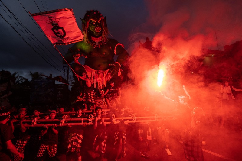 Pemuda Bali membawa ogoh-ogoh, boneka raksasa yang tampak mengancam saat pawai ogoh-ogoh pada malam Nyepi, Hari Raya Nyepi umat Hindu Bali yang menandai datangnya tahun baru Saka bulan pada 20 Maret 2023 di Tegalalang Desa, Gianyar, Bali, Indonesia. Pemuda Bali membawa ogoh-ogoh, boneka raksasa yang tampak mengancam saat pawai ogoh-ogoh pada malam Nyepi, Hari Raya Nyepi umat Hindu Bali yang menandai datangnya tahun baru Saka bulan pada 20 Maret 2023 di Tegalalang Desa, Gianyar, Bali, Indonesia. Umat Hindu di Bali melakukan serangkaian ritual pada awal Maret untuk merayakan tahun baru Imlek yang berpuncak pada perayaan Nyepi. Ogoh-ogoh menjadi salah satu pawai di awal tahun 1980-an. Sebelumnya, para peserta berkeliaran di jalan-jalan membawa obor bambu dan membuat suara keras dengan instrumen perkusi untuk menakut-nakuti setan. Di Bali masa kini, mayoritas ogoh-ogoh dibangun oleh anggota seka teruna teruni, sayap pemuda banjar. Nyepi berasal dari kata sepi atau sipeng yang artinya sepi, sepi, hening, nol, kosong, tidak ramai, tidak berisik, dan tidak ada aktivitas. Sejak tahun 1983, Nyepi menjadi hari libur nasional. Perayaan hari raya Nyepi bagi umat Hindu Bali di Indonesia merupakan kesempatan untuk refleksi diri yang disebut dengan mulat sarira. Semua penghuni dan pengunjung diwajibkan untuk mematuhi aturan yang disebut Catur Brata Penyepian, yang terdiri dari: tidak menyalakan api atau nyala api, tidak melakukan kegiatan yang menyenangkan, tidak bekerja atau bekerja, dan tidak melakukan perjalanan. (Agung Parameswara/Getty Images)