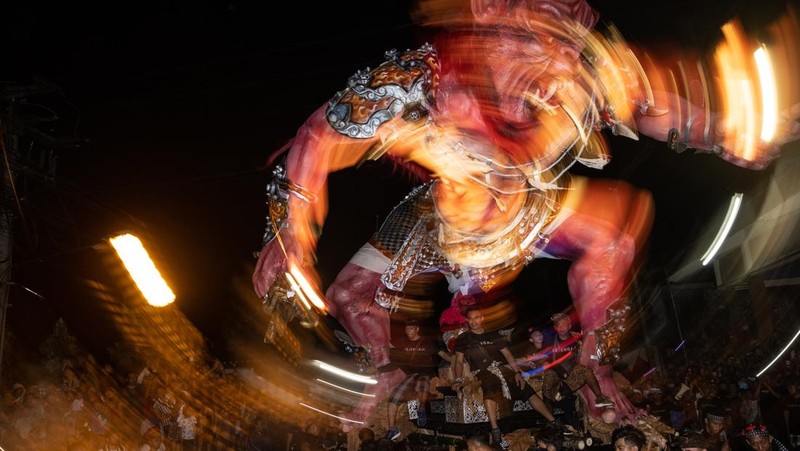 Pemuda Bali membawa ogoh-ogoh, boneka raksasa yang tampak mengancam saat pawai ogoh-ogoh pada malam Nyepi, Hari Raya Nyepi umat Hindu Bali yang menandai datangnya tahun baru Saka bulan pada 20 Maret 2023 di Tegalalang Desa, Gianyar, Bali, Indonesia. Umat Hindu di Bali melakukan serangkaian ritual pada awal Maret untuk merayakan tahun baru Imlek yang berpuncak pada perayaan Nyepi. Ogoh-ogoh menjadi salah satu pawai di awal tahun 1980-an. Sebelumnya, para peserta berkeliaran di jalan-jalan membawa obor bambu dan membuat suara keras dengan instrumen perkusi untuk menakut-nakuti setan. Di Bali masa kini, mayoritas ogoh-ogoh dibangun oleh anggota seka teruna teruni, sayap pemuda banjar. Nyepi berasal dari kata sepi atau sipeng yang artinya sepi, sepi, hening, nol, kosong, tidak ramai, tidak berisik, dan tidak ada aktivitas. Sejak tahun 1983, Nyepi menjadi hari libur nasional. Perayaan hari raya Nyepi bagi umat Hindu Bali di Indonesia merupakan kesempatan untuk refleksi diri yang disebut dengan mulat sarira. Semua penghuni dan pengunjung diwajibkan untuk mematuhi aturan yang disebut Catur Brata Penyepian, yang terdiri dari: tidak menyalakan api atau nyala api, tidak melakukan kegiatan yang menyenangkan, tidak bekerja atau bekerja, dan tidak melakukan perjalanan. (Agung Parameswara/Getty Images)