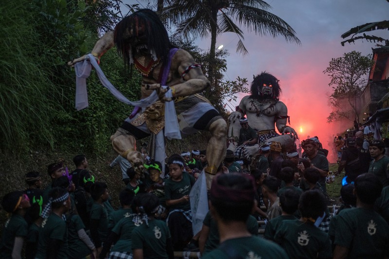 Pemuda Bali membawa ogoh-ogoh, boneka raksasa yang tampak mengancam saat pawai ogoh-ogoh pada malam Nyepi, Hari Raya Nyepi umat Hindu Bali yang menandai datangnya tahun baru Saka bulan pada 20 Maret 2023 di Tegalalang Desa, Gianyar, Bali, Indonesia. Umat Hindu di Bali melakukan serangkaian ritual pada awal Maret untuk merayakan tahun baru Imlek yang berpuncak pada perayaan Nyepi. Ogoh-ogoh menjadi salah satu pawai di awal tahun 1980-an. Sebelumnya, para peserta berkeliaran di jalan-jalan membawa obor bambu dan membuat suara keras dengan instrumen perkusi untuk menakut-nakuti setan. Di Bali masa kini, mayoritas ogoh-ogoh dibangun oleh anggota seka teruna teruni, sayap pemuda banjar. Nyepi berasal dari kata sepi atau sipeng yang artinya sepi, sepi, hening, nol, kosong, tidak ramai, tidak berisik, dan tidak ada aktivitas. Sejak tahun 1983, Nyepi menjadi hari libur nasional. Perayaan hari raya Nyepi bagi umat Hindu Bali di Indonesia merupakan kesempatan untuk refleksi diri yang disebut dengan mulat sarira. Semua penghuni dan pengunjung diwajibkan untuk mematuhi aturan yang disebut Catur Brata Penyepian, yang terdiri dari: tidak menyalakan api atau nyala api, tidak melakukan kegiatan yang menyenangkan, tidak bekerja atau bekerja, dan tidak melakukan perjalanan. (Agung Parameswara/Getty Images)