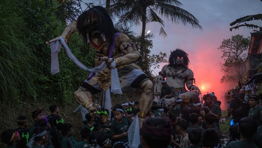 Pemuda Bali membawa ogoh-ogoh, boneka raksasa yang tampak mengancam saat pawai ogoh-ogoh pada malam Nyepi, Hari Raya Nyepi umat Hindu Bali yang menandai datangnya tahun baru Saka bulan pada 20 Maret 2023 di Tegalalang Desa, Gianyar, Bali, Indonesia. Umat Hindu di Bali melakukan serangkaian ritual pada awal Maret untuk merayakan tahun baru Imlek yang berpuncak pada perayaan Nyepi. Ogoh-ogoh menjadi salah satu pawai di awal tahun 1980-an. Sebelumnya, para peserta berkeliaran di jalan-jalan membawa obor bambu dan membuat suara keras dengan instrumen perkusi untuk menakut-nakuti setan. Di Bali masa kini, mayoritas ogoh-ogoh dibangun oleh anggota seka teruna teruni, sayap pemuda banjar. Nyepi berasal dari kata sepi atau sipeng yang artinya sepi, sepi, hening, nol, kosong, tidak ramai, tidak berisik, dan tidak ada aktivitas. Sejak tahun 1983, Nyepi menjadi hari libur nasional. Perayaan hari raya Nyepi bagi umat Hindu Bali di Indonesia merupakan kesempatan untuk refleksi diri yang disebut dengan mulat sarira. Semua penghuni dan pengunjung diwajibkan untuk mematuhi aturan yang disebut Catur Brata Penyepian, yang terdiri dari: tidak menyalakan api atau nyala api, tidak melakukan kegiatan yang menyenangkan, tidak bekerja atau bekerja, dan tidak melakukan perjalanan. (Agung Parameswara/Getty Images)