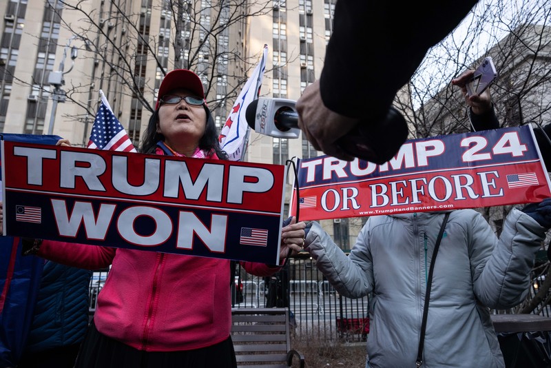Pendukung mantan Presiden Donald Trump melakukan protes di dekat kantor Kejaksaan Distrik Manhattan Alvin Brag dan Pengadilan Kriminal New York County pada 20 Maret 2023 di New York City. Trump memposting di media sosial bahwa dia berharap akan ditangkap sehubungan dengan penyelidikan di New York atas skema uang tutup mulut yang melibatkan aktris film dewasa Stormy Daniels dan meminta para pendukungnya untuk memprotes tindakan tersebut. (Alexi J. Rosenfeld/Getty Images)