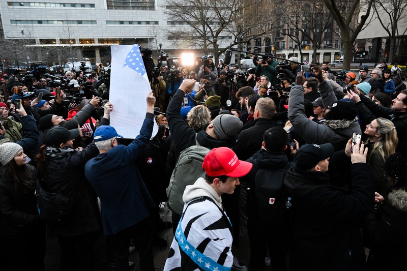 Pendukung mantan Presiden Donald Trump melakukan protes di dekat kantor Kejaksaan Distrik Manhattan Alvin Brag dan Pengadilan Kriminal New York County pada 20 Maret 2023 di New York City. Trump memposting di media sosial bahwa dia berharap akan ditangkap sehubungan dengan penyelidikan di New York atas skema uang tutup mulut yang melibatkan aktris film dewasa Stormy Daniels dan meminta para pendukungnya untuk memprotes tindakan tersebut. (Alexi J. Rosenfeld/Getty Images)