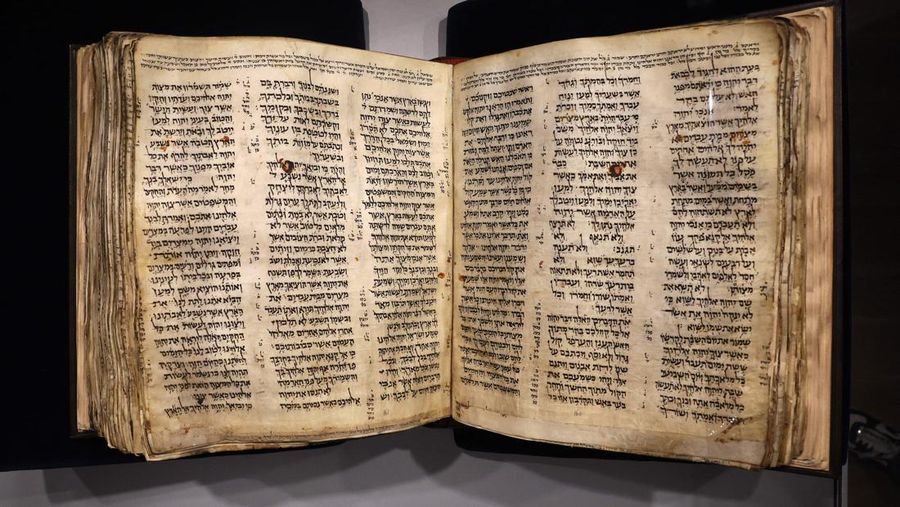 Orang-orang melihat Codex Sassoon, edisi paling awal dari Alkitab Ibrani, pada 22 Maret 2023 di Museum Orang Yahudi ANU di Tel Aviv. - Manuskrip, yang diyakini berusia lebih dari 1.000 tahun, akan dijual di lelang di New York dengan harga sekitar $50 juta. (JACK GUEZ/AFP via Getty Images)