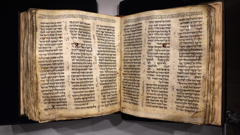 Orang-orang melihat Codex Sassoon, edisi paling awal dari Alkitab Ibrani, pada 22 Maret 2023 di Museum Orang Yahudi ANU di Tel Aviv. - Manuskrip, yang diyakini berusia lebih dari 1.000 tahun, akan dijual di lelang di New York dengan harga sekitar $50 juta. (JACK GUEZ/AFP via Getty Images)