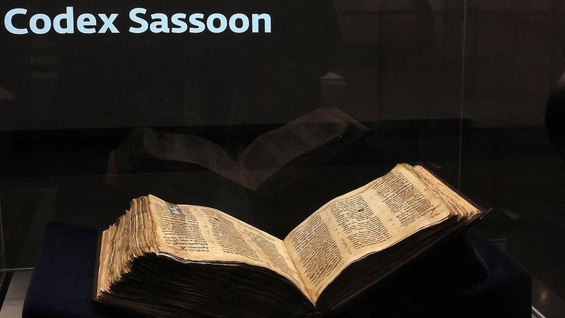 Orang-orang melihat Codex Sassoon, edisi paling awal dari Alkitab Ibrani, pada 22 Maret 2023 di Museum Orang Yahudi ANU di Tel Aviv. - Manuskrip, yang diyakini berusia lebih dari 1.000 tahun, akan dijual di lelang di New York dengan harga sekitar $50 juta. (JACK GUEZ/AFP via Getty Images)