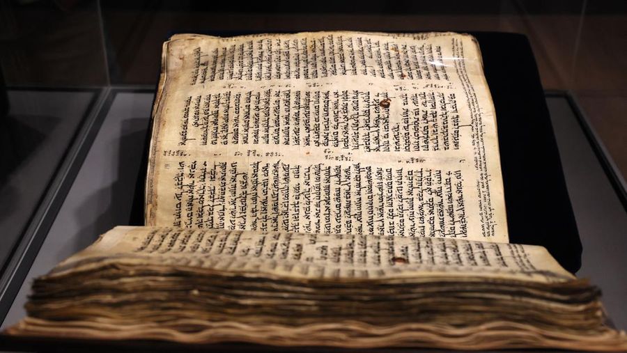 Orang-orang melihat Codex Sassoon, edisi paling awal dari Alkitab Ibrani, pada 22 Maret 2023 di Museum Orang Yahudi ANU di Tel Aviv. - Manuskrip, yang diyakini berusia lebih dari 1.000 tahun, akan dijual di lelang di New York dengan harga sekitar $50 juta. (JACK GUEZ/AFP via Getty Images)
