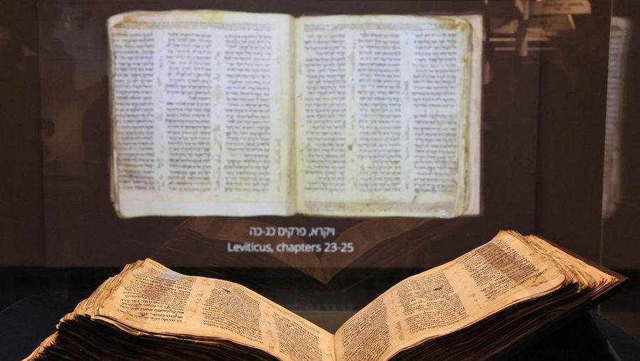 Orang-orang melihat Codex Sassoon, edisi paling awal dari Alkitab Ibrani, pada 22 Maret 2023 di Museum Orang Yahudi ANU di Tel Aviv. - Manuskrip, yang diyakini berusia lebih dari 1.000 tahun, akan dijual di lelang di New York dengan harga sekitar $50 juta. (JACK GUEZ/AFP via Getty Images)