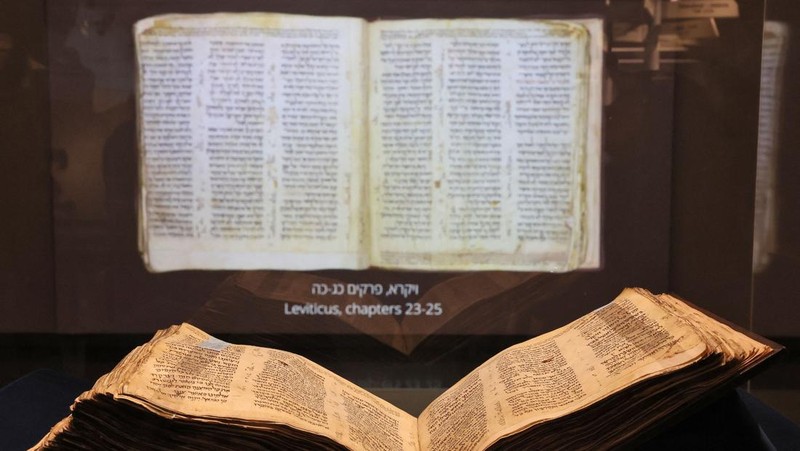 Orang-orang melihat Codex Sassoon, edisi paling awal dari Alkitab Ibrani, pada 22 Maret 2023 di Museum Orang Yahudi ANU di Tel Aviv. - Manuskrip, yang diyakini berusia lebih dari 1.000 tahun, akan dijual di lelang di New York dengan harga sekitar $50 juta. (JACK GUEZ/AFP via Getty Images)