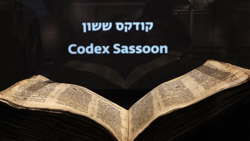 Orang-orang melihat Codex Sassoon, edisi paling awal dari Alkitab Ibrani, pada 22 Maret 2023 di Museum Orang Yahudi ANU di Tel Aviv. - Manuskrip, yang diyakini berusia lebih dari 1.000 tahun, akan dijual di lelang di New York dengan harga sekitar $50 juta. (JACK GUEZ/AFP via Getty Images)